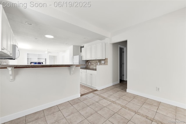 25044 Comfort, Center Line, MI 48015 - kitchen featuring a peninsula, a kitchen breakfast bar, light tile patterned flooring, white cabinetry, and white appliances