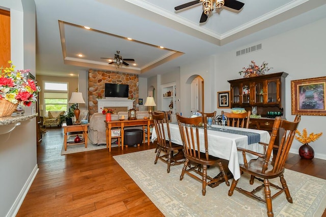 8734 Oakland Hills Cir Unit 6, Portage, MI 49024 - dining room featuring a ceiling fan, a raised ceiling, crown molding, a stone fireplace, and hardwood / wood-style flooring