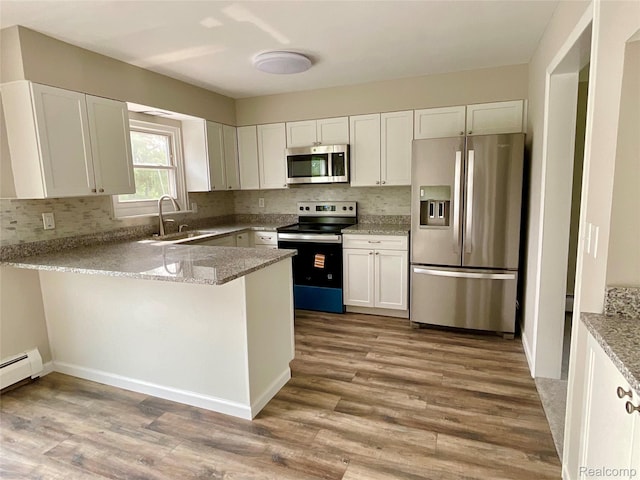 3615 N Mill Rd, Dryden, MI 48428 - kitchen featuring appliances with stainless steel finishes, backsplash, a peninsula, and light wood finished floors