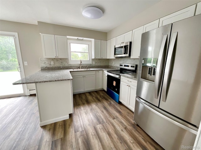 3615 N Mill Rd, Dryden, MI 48428 - kitchen with appliances with stainless steel finishes, a peninsula, dark wood-type flooring, and tasteful backsplash