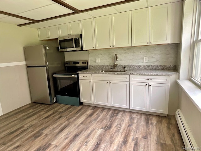 3615 N Mill Rd, Dryden, MI 48428 - kitchen with appliances with stainless steel finishes, a baseboard radiator, wood finished floors, backsplash, and a wainscoted wall