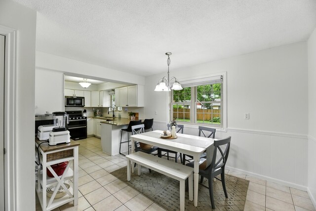 1548 Old Hickory Ln, Saint Joseph, MI 49085 - dining space featuring light tile patterned floors, wainscoting, a chandelier, and a textured ceiling