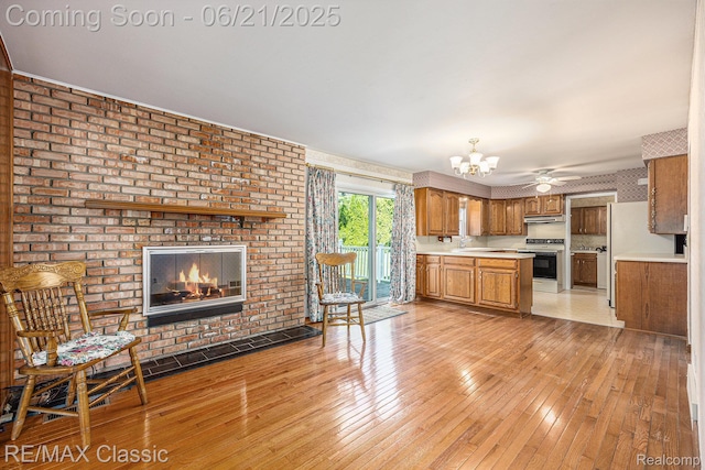 1925 Dawn Ridge Rd, Commerce Twp, MI 48390 - kitchen featuring brown cabinetry, a fireplace, under cabinet range hood, white appliances, and light countertops