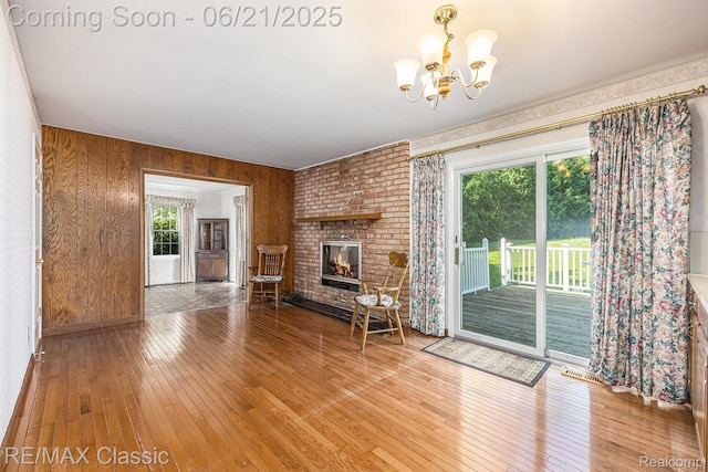 1925 Dawn Ridge Rd, Commerce Twp, MI 48390 - unfurnished living room featuring hardwood / wood-style flooring, a chandelier, wooden walls, and a fireplace