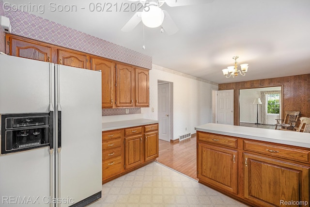 1925 Dawn Ridge Rd, Commerce Twp, MI 48390 - kitchen with white fridge with ice dispenser, brown cabinetry, light floors, light countertops, and wallpapered walls