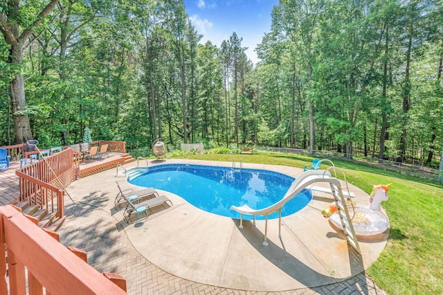 13421 Woodland Ct, Big Rapids, MI 49307 - outdoor pool with a water slide, a wooden deck, a patio, and a view of trees