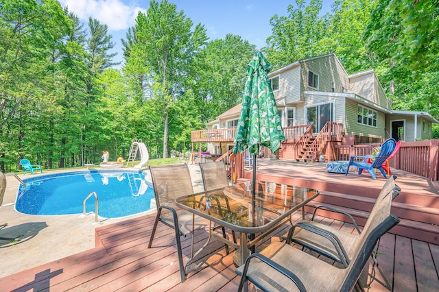13421 Woodland Ct, Big Rapids, MI 49307 - outdoor pool featuring a wooden deck, a water slide, stairway, view of wooded area, and a patio area