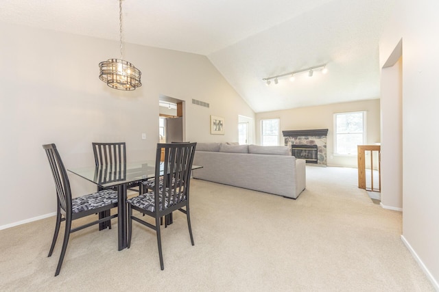 492 Colin Cir, Ann Arbor, MI 48103 - dining area with light colored carpet, a chandelier, vaulted ceiling, a fireplace, and rail lighting