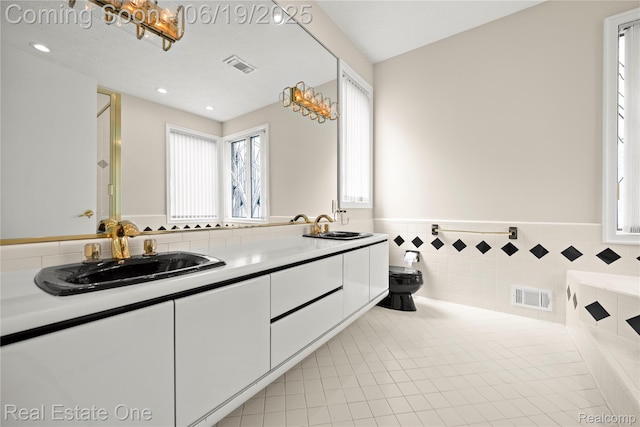 2505 Cedar Key Dr, Lake Orion, MI 48360 - bathroom with double vanity, a wainscoted wall, tiled bath, tile walls, and recessed lighting