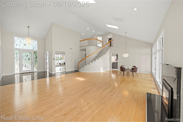 2505 Cedar Key Dr, Lake Orion, MI 48360 - unfurnished living room featuring a chandelier, high vaulted ceiling, stairway, wood finished floors, and recessed lighting