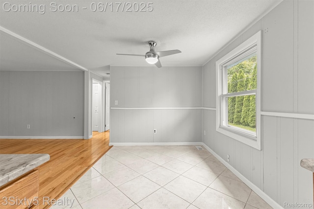 36513 Evans St, New Boston, MI 48164 - empty room featuring ceiling fan, a textured ceiling, light wood-style floors, and a decorative wall
