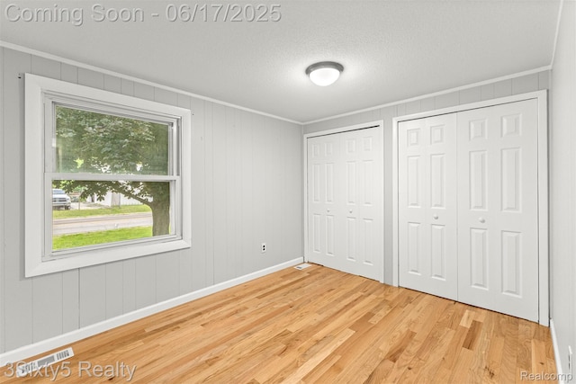 36513 Evans St, New Boston, MI 48164 - unfurnished bedroom featuring ornamental molding, wood finished floors, multiple closets, and a textured ceiling