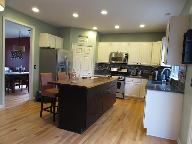 1995 Frances Way, Ypsilanti, MI 48198 - kitchen featuring stainless steel appliances, a center island, wood counters, decorative backsplash, and light wood-type flooring
