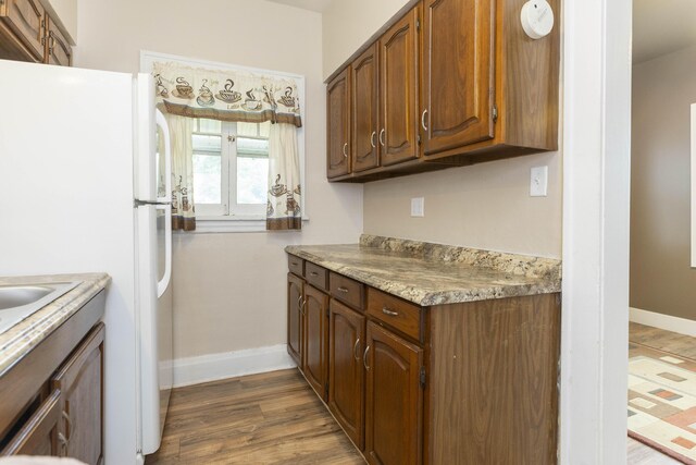 318 Cecil St, Buchanan, MI 49107 - kitchen with freestanding refrigerator, dark wood finished floors, light countertops, and brown cabinets