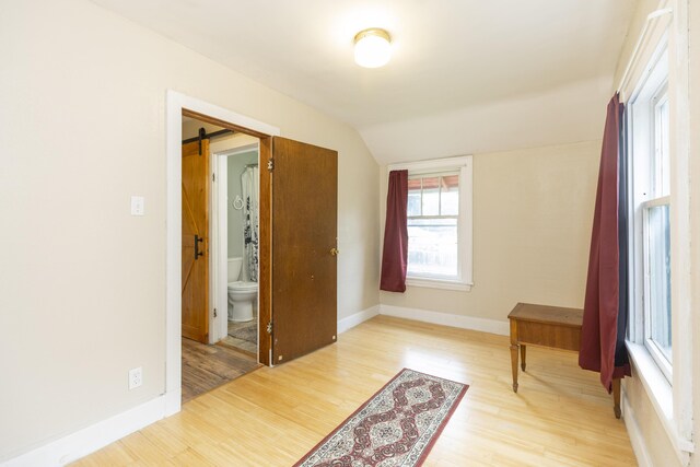 318 Cecil St, Buchanan, MI 49107 - interior space featuring lofted ceiling, light wood-style floors, connected bathroom, and a barn door