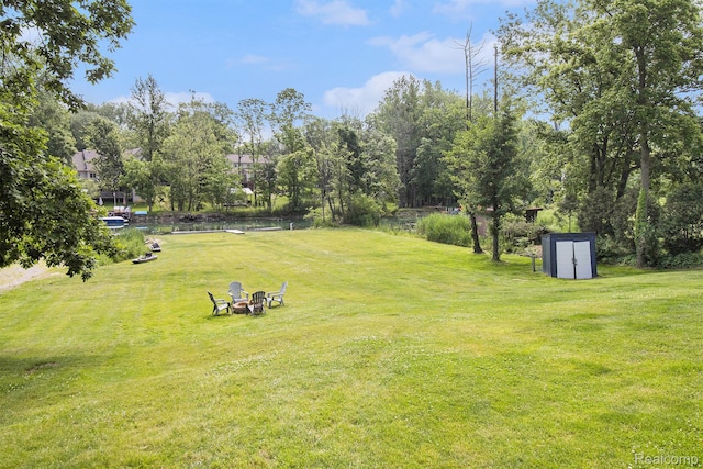 22085 Thorofare Rd, Grosse Ile, MI 48138 - view of green lawn with a storage shed, an outdoor fire pit, and view of scattered trees