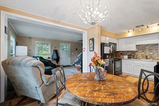 17013 Smugglers Cove St, Clinton Township, MI 48038 - dining space featuring stairs, light wood-style flooring, a chandelier, and ornamental molding