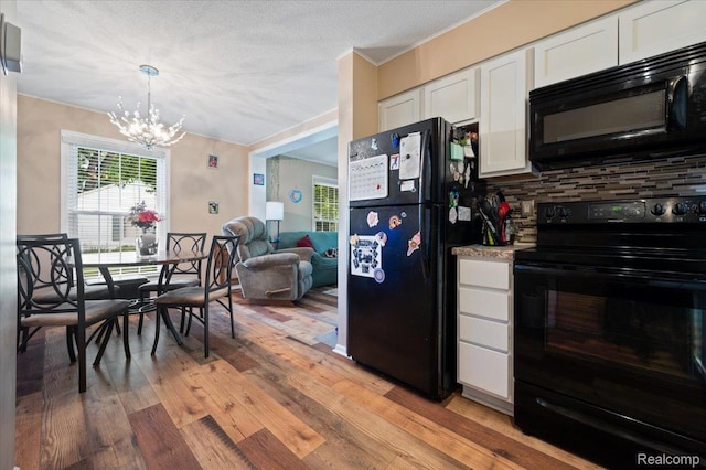 17013 Smugglers Cove St, Clinton Township, MI 48038 - kitchen featuring black appliances, light wood-style flooring, a chandelier, decorative backsplash, and white cabinetry