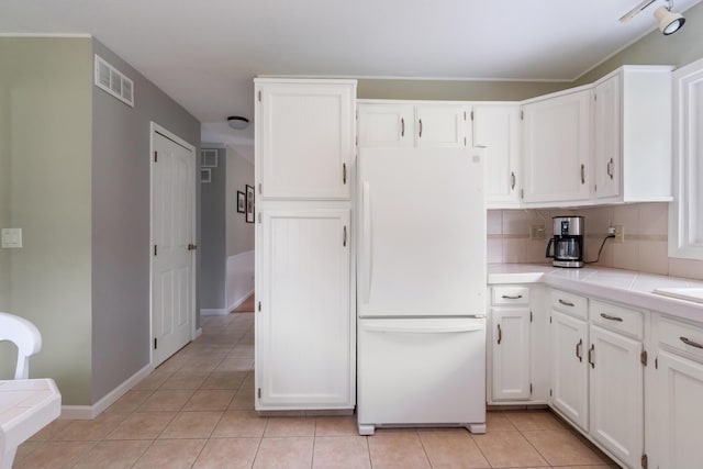 3125 Fawn Ln, Jackson, MI 49201 - kitchen featuring freestanding refrigerator, light tile patterned floors, white cabinets, and tile countertops