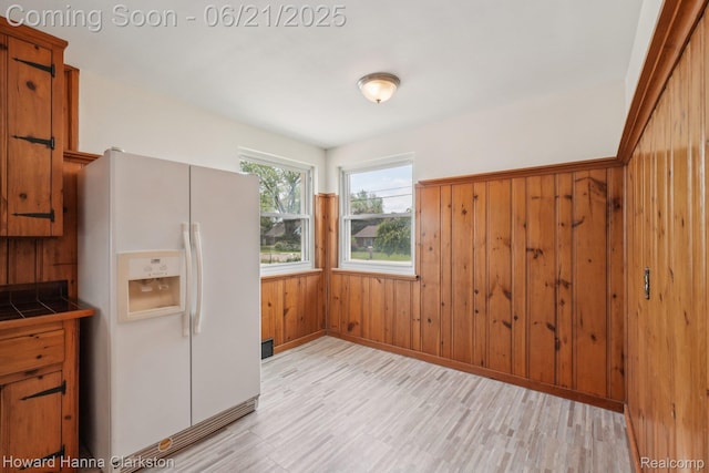 5766 Corunna Ave, Clarkston, MI 48346 - kitchen featuring white refrigerator with ice dispenser, tile countertops, wood walls, light wood finished floors, and brown cabinets