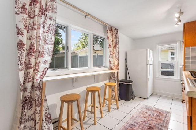 317 Cherry St, South Haven, MI 49090 - kitchen with freestanding refrigerator, light tile patterned floors, and a kitchen breakfast bar