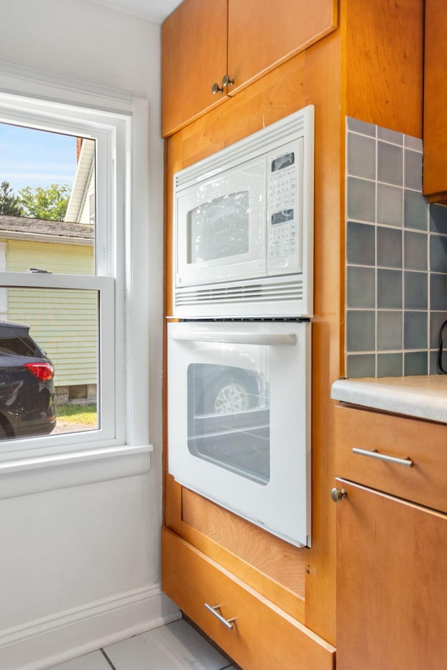 317 Cherry St, South Haven, MI 49090 - kitchen with white appliances, brown cabinetry, light countertops, and tile patterned flooring