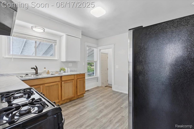 3920 Clark St, Canton, MI 48184 - kitchen featuring freestanding refrigerator, black range with gas cooktop, light wood-type flooring, brown cabinetry, and light countertops