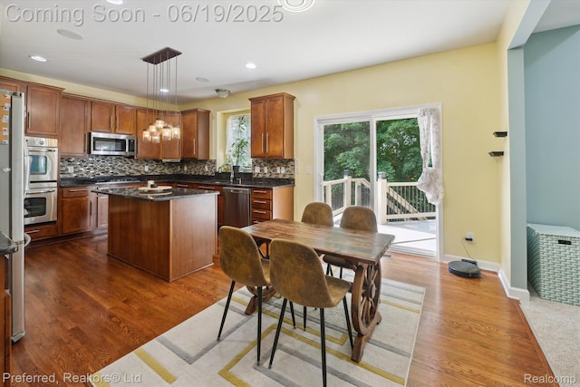51159 Luke Ln, Novi, MI 48374 - kitchen featuring appliances with stainless steel finishes, dark countertops, a center island, backsplash, and dark wood finished floors