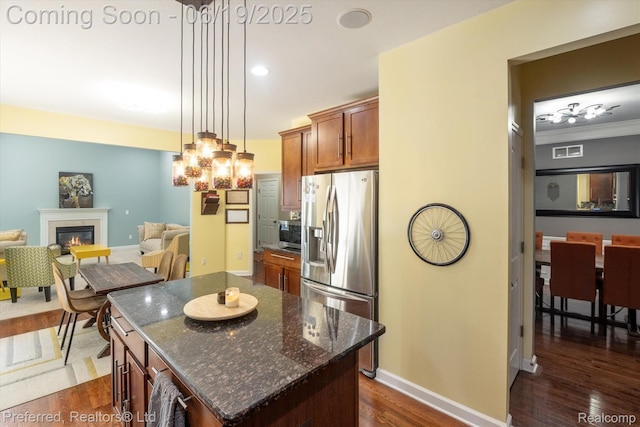 51159 Luke Ln, Novi, MI 48374 - kitchen featuring stainless steel appliances, a glass covered fireplace, decorative light fixtures, brown cabinetry, and dark wood finished floors