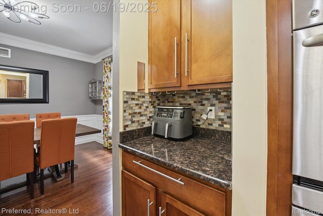 51159 Luke Ln, Novi, MI 48374 - kitchen with ornamental molding, dark wood-type flooring, brown cabinetry, dark stone countertops, and backsplash