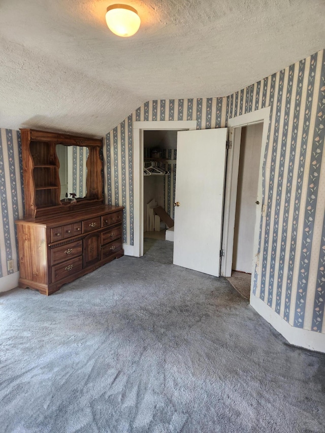 222 Scribner St, Delton, MI 49046 - unfurnished bedroom with wallpapered walls, a textured ceiling, carpet, and a spacious closet
