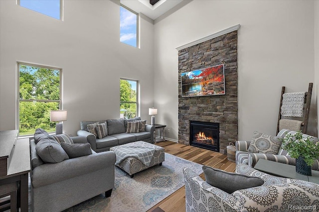 966 Wynstone Cir N, Oakland, MI 48363 - living room featuring wood finished floors, a towering ceiling, a stone fireplace, and healthy amount of natural light