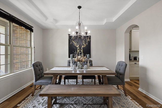 966 Wynstone Cir N, Oakland, MI 48363 - dining room featuring a chandelier, a tray ceiling, wood finished floors, and arched walkways