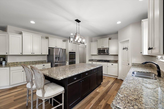 966 Wynstone Cir N, Oakland, MI 48363 - kitchen featuring appliances with stainless steel finishes, a kitchen island, white cabinets, a breakfast bar area, and recessed lighting