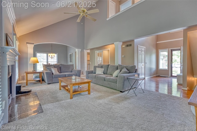 1070 Pointe Place Ct, Rochester, MI 48307 - carpeted living room featuring ornate columns, high vaulted ceiling, a ceiling fan, a fireplace with raised hearth, and arched walkways