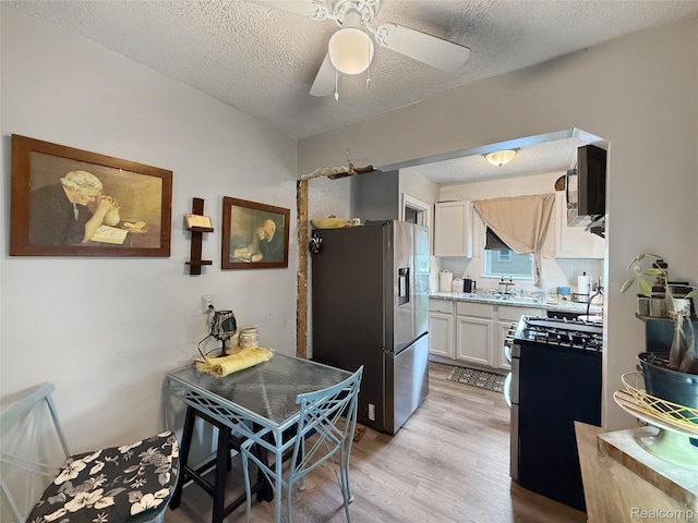 20115 Pelkey St, Detroit, MI 48205 - kitchen with stainless steel appliances, light wood-type flooring, a textured ceiling, white cabinets, and light countertops