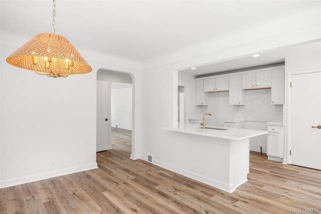807 Barrington Rd, Grosse Pointe Park, MI 48230 - kitchen with arched walkways, light wood-style floors, recessed lighting, a chandelier, and a peninsula