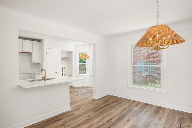 807 Barrington Rd, Grosse Pointe Park, MI 48230 - kitchen featuring a chandelier, light wood-style flooring, white cabinets, and pendant lighting