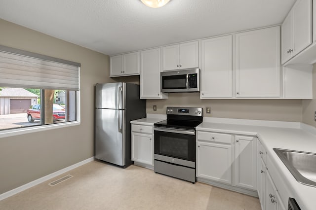 3745 Cedaridge Rd, Kalamazoo, MI 49008 - kitchen with stainless steel appliances, white cabinets, light countertops, and a textured ceiling