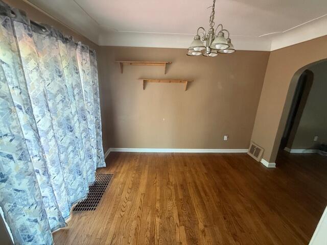 6185 Wing Ave SE, Grand Rapids, MI 49512 - unfurnished dining area featuring arched walkways, wood finished floors, and a chandelier