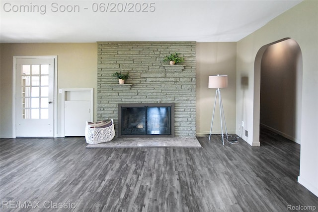 1861 Ladd Rd, Wolverine Lake, MI 48390 - unfurnished living room featuring wood finished floors, a stone fireplace, and arched walkways