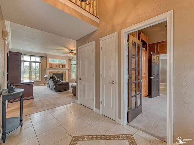 831 Saint James Park Ave, Monroe, MI 48161 - foyer entrance featuring light carpet, light tile patterned floors, a fireplace, ceiling fan, and a textured wall