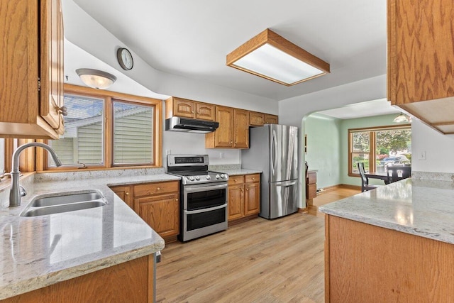 1228 Orchid St, Waterford, MI 48328 - kitchen featuring appliances with stainless steel finishes, under cabinet range hood, light wood finished floors, brown cabinets, and arched walkways