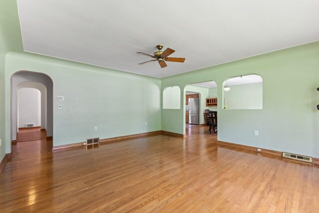 1228 Orchid St, Waterford, MI 48328 - spare room featuring arched walkways, ceiling fan, and wood finished floors
