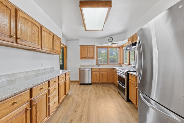 1228 Orchid St, Waterford, MI 48328 - kitchen with appliances with stainless steel finishes, light wood-style flooring, light stone countertops, under cabinet range hood, and brown cabinets