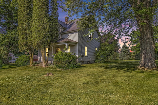 3833 S Baldwin Ave, Fremont, MI 49412 - view of side of home featuring a chimney, a lawn, a porch, and a metal roof