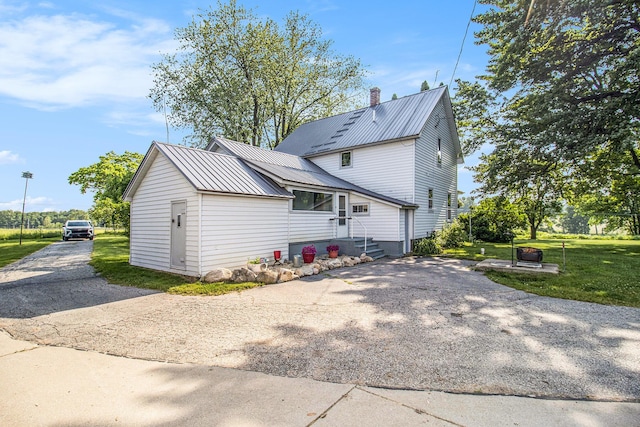 3833 S Baldwin Ave, Fremont, MI 49412 - rear view of property with asphalt driveway, a metal roof, a lawn, a chimney, and entry steps