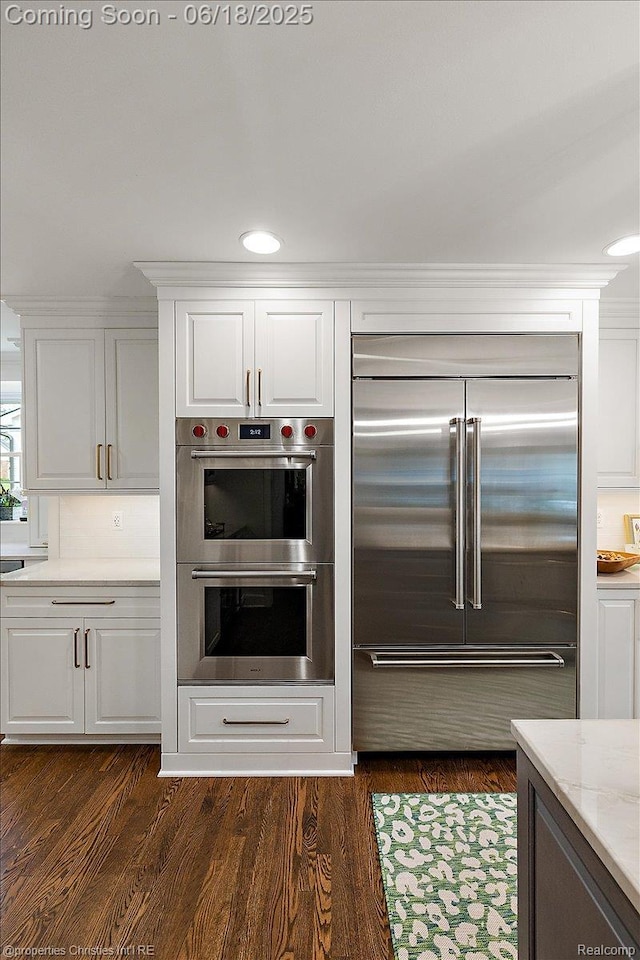 586 Fairfax St, Birmingham, MI 48009 - kitchen featuring appliances with stainless steel finishes, white cabinets, light stone countertops, dark wood finished floors, and recessed lighting