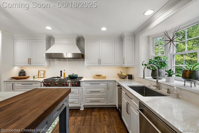 586 Fairfax St, Birmingham, MI 48009 - kitchen with wall chimney exhaust hood, stainless steel appliances, white cabinetry, wood counters, and tasteful backsplash