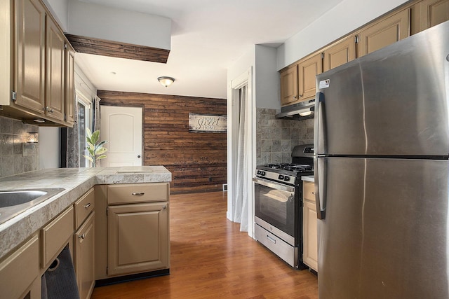 1602 Mccann Rd, Hastings, MI 49058 - kitchen featuring stainless steel appliances, under cabinet range hood, tasteful backsplash, wood finished floors, and wood walls